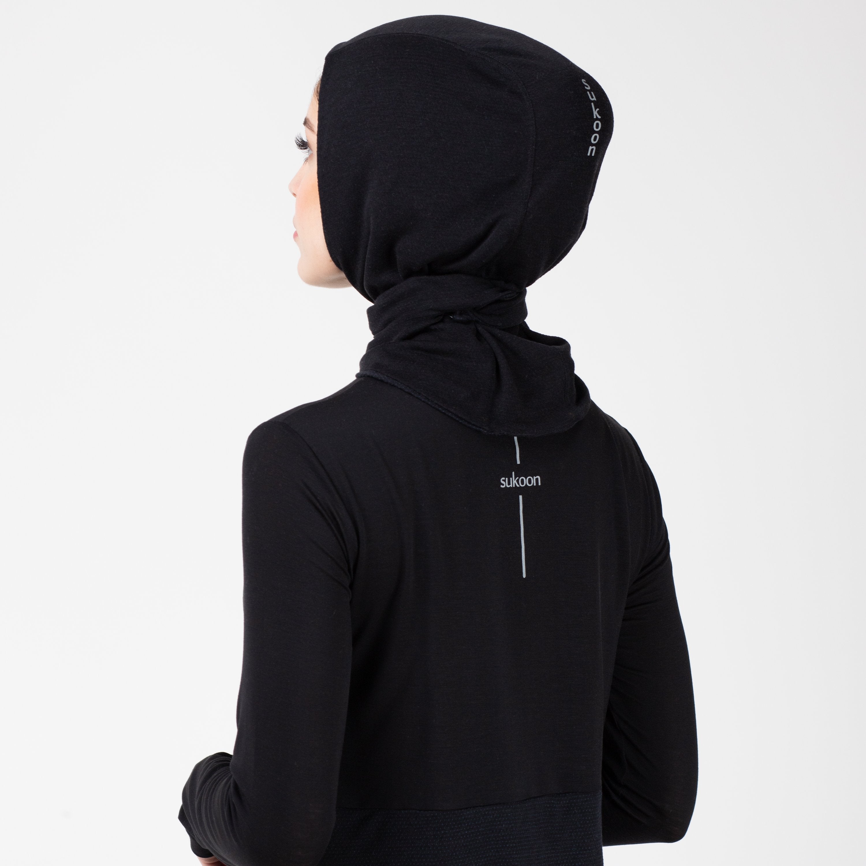 Back detail of a woman in a black shirt with a matching black HAWA hijab.
