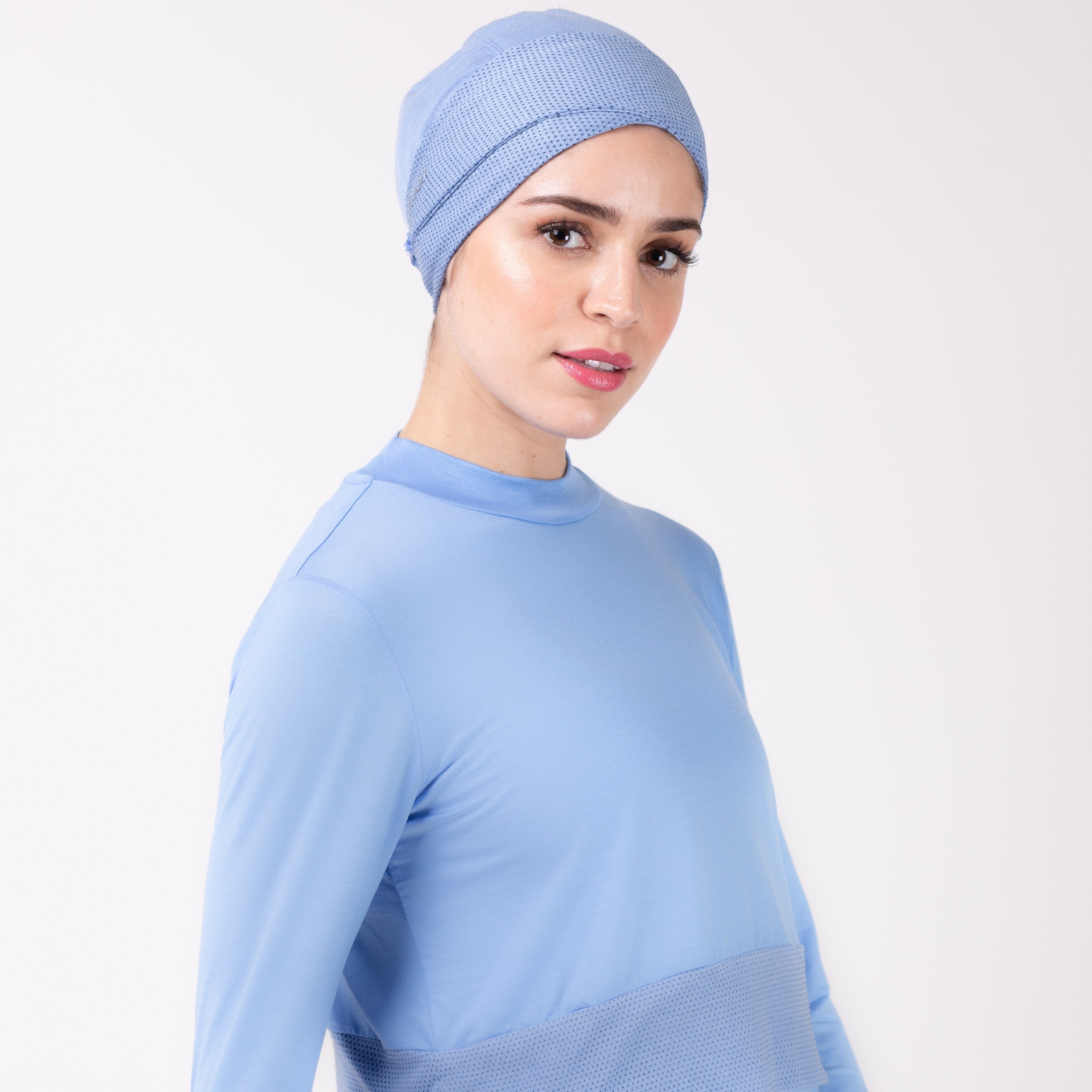 Woman facing right in a sky blue shirt with matching sky blue HAWA headwrap.