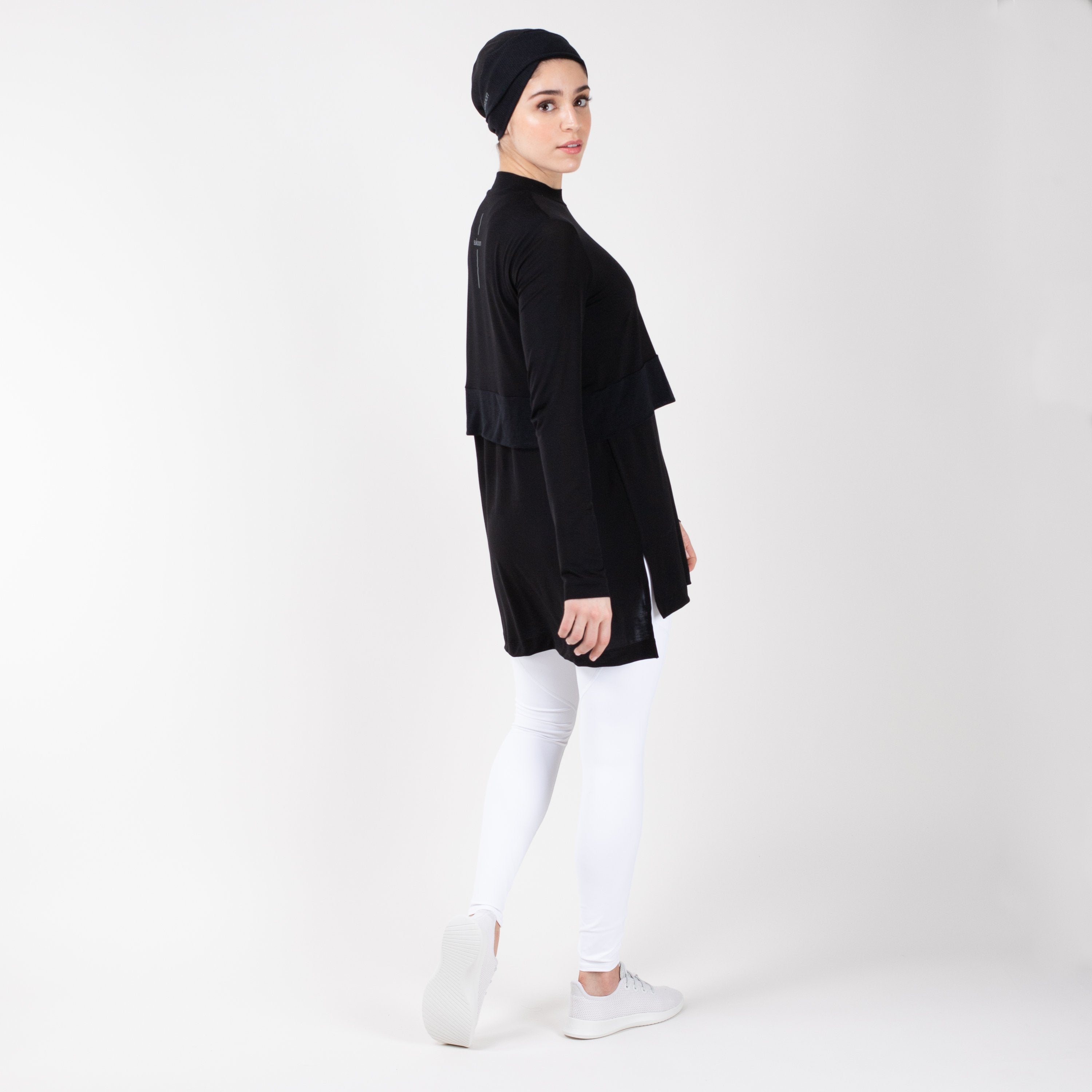Woman looking over her right shoulder in a black HAWA step tee.