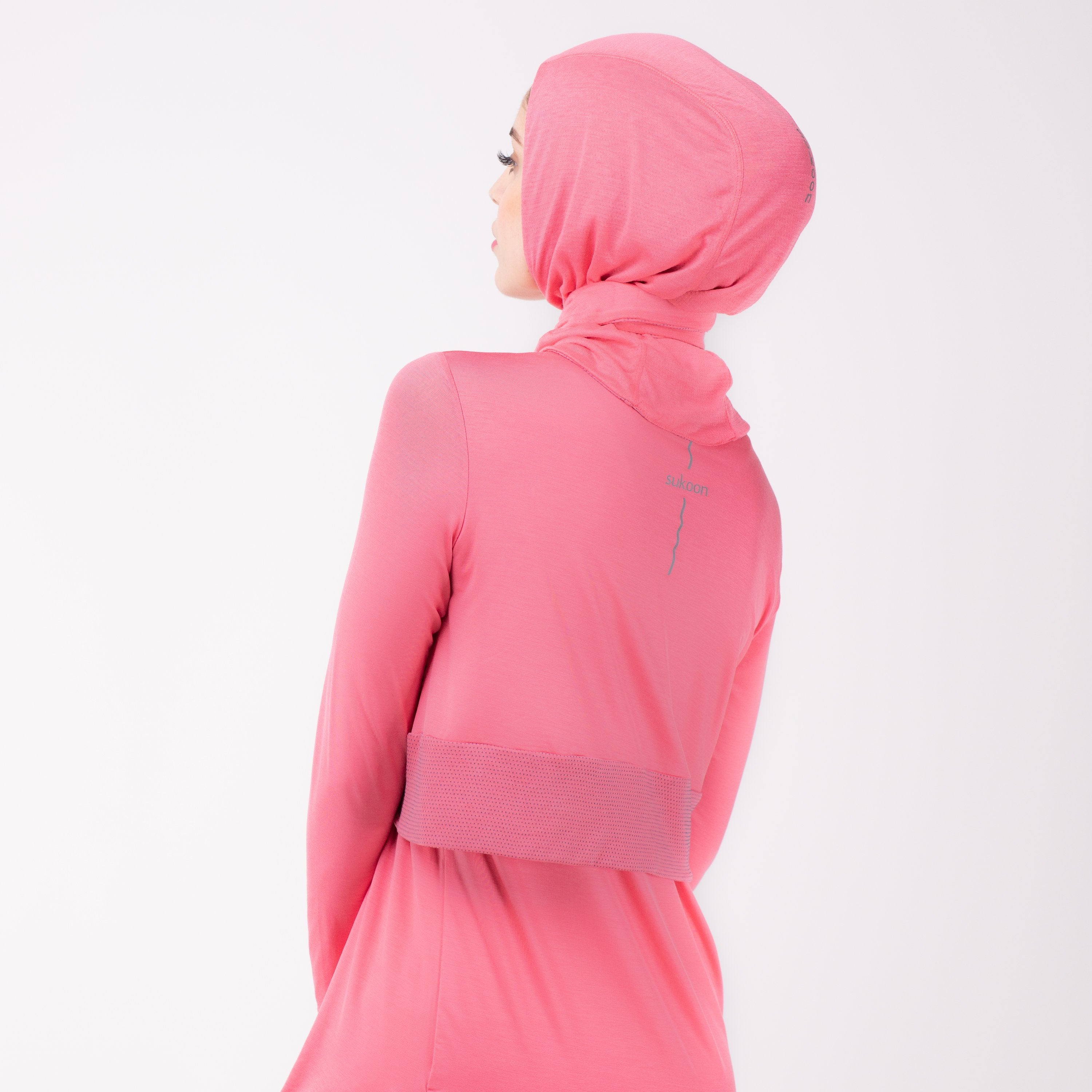 Back detail of a woman in a pink shirt with a matching pink HAWA hijab.