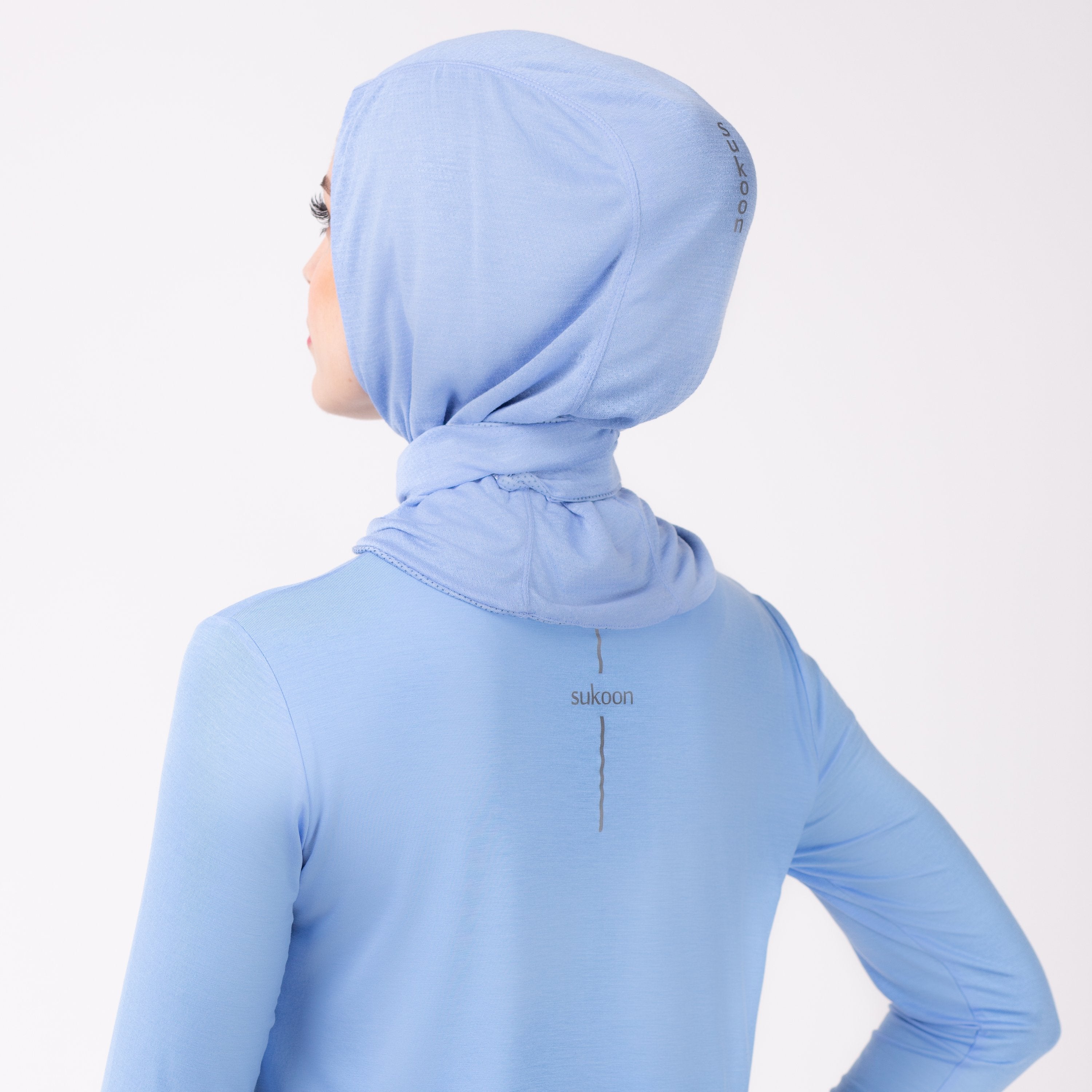 Back detail of a woman in a sky blue shirt with a matching sky blue HAWA hijab.