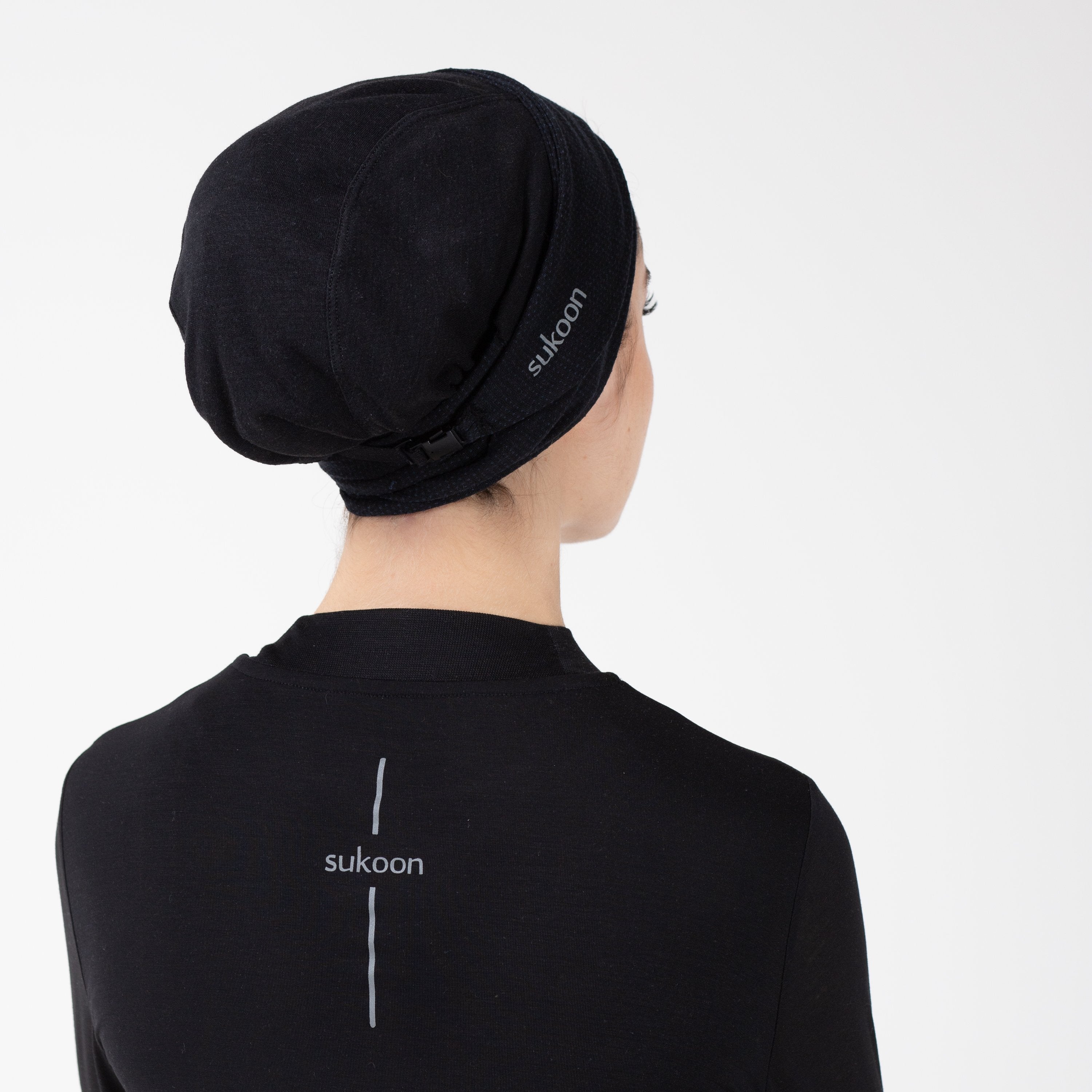 Back detail of a woman in a black shirt with a matching black HAWA headwrap.