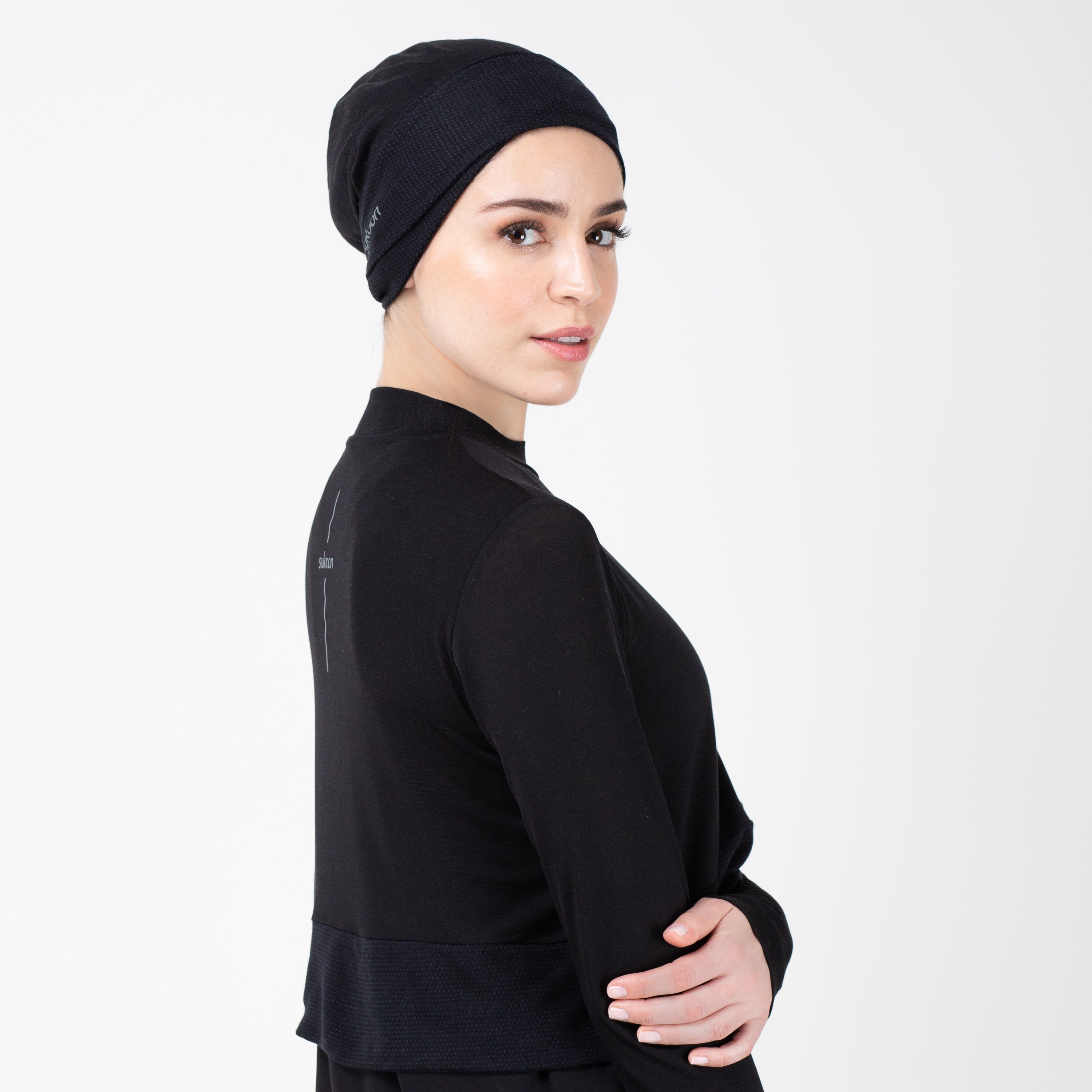 Woman facing right in a black shirt with matching black HAWA headwrap.