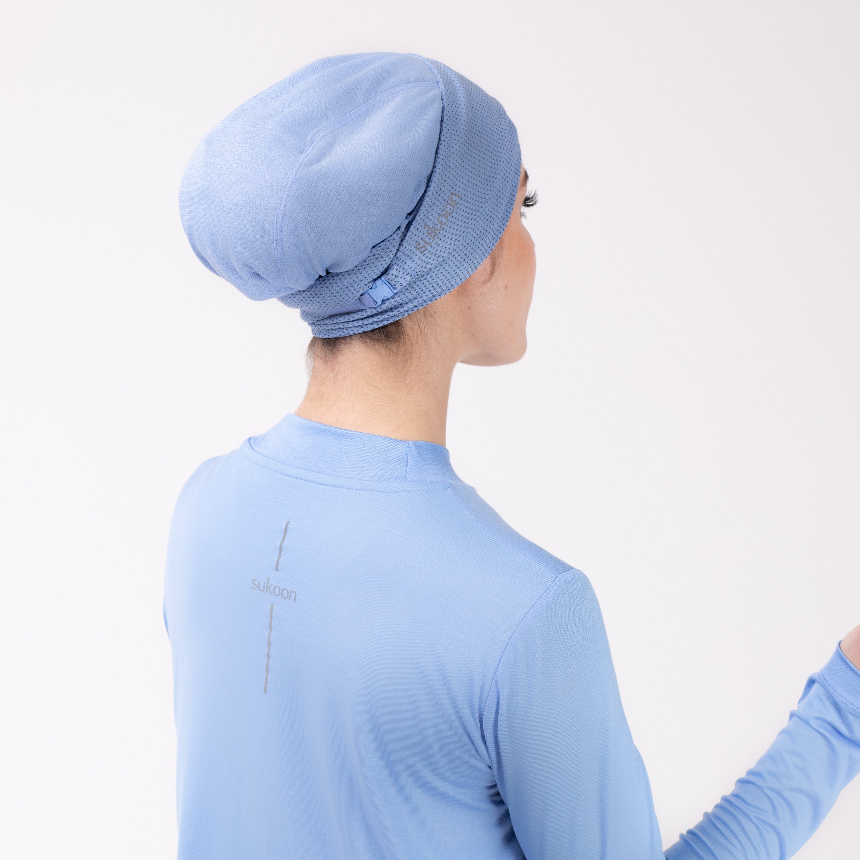 Back detail of woman in sky blue shirt with matching sky blue HAWA headwrap. 