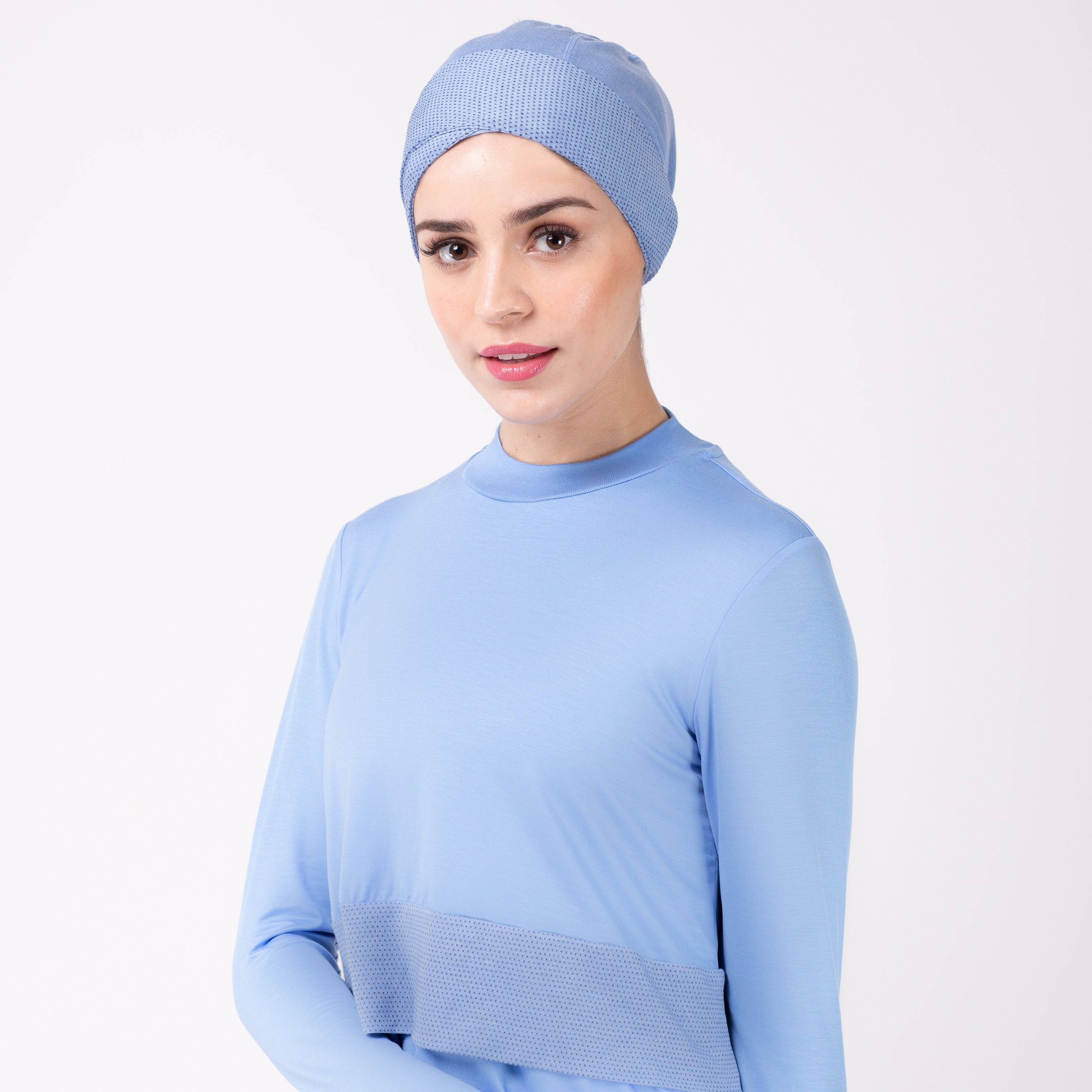 Woman facing left in sky blue shirt and matching sky blue HAWA headwrap.