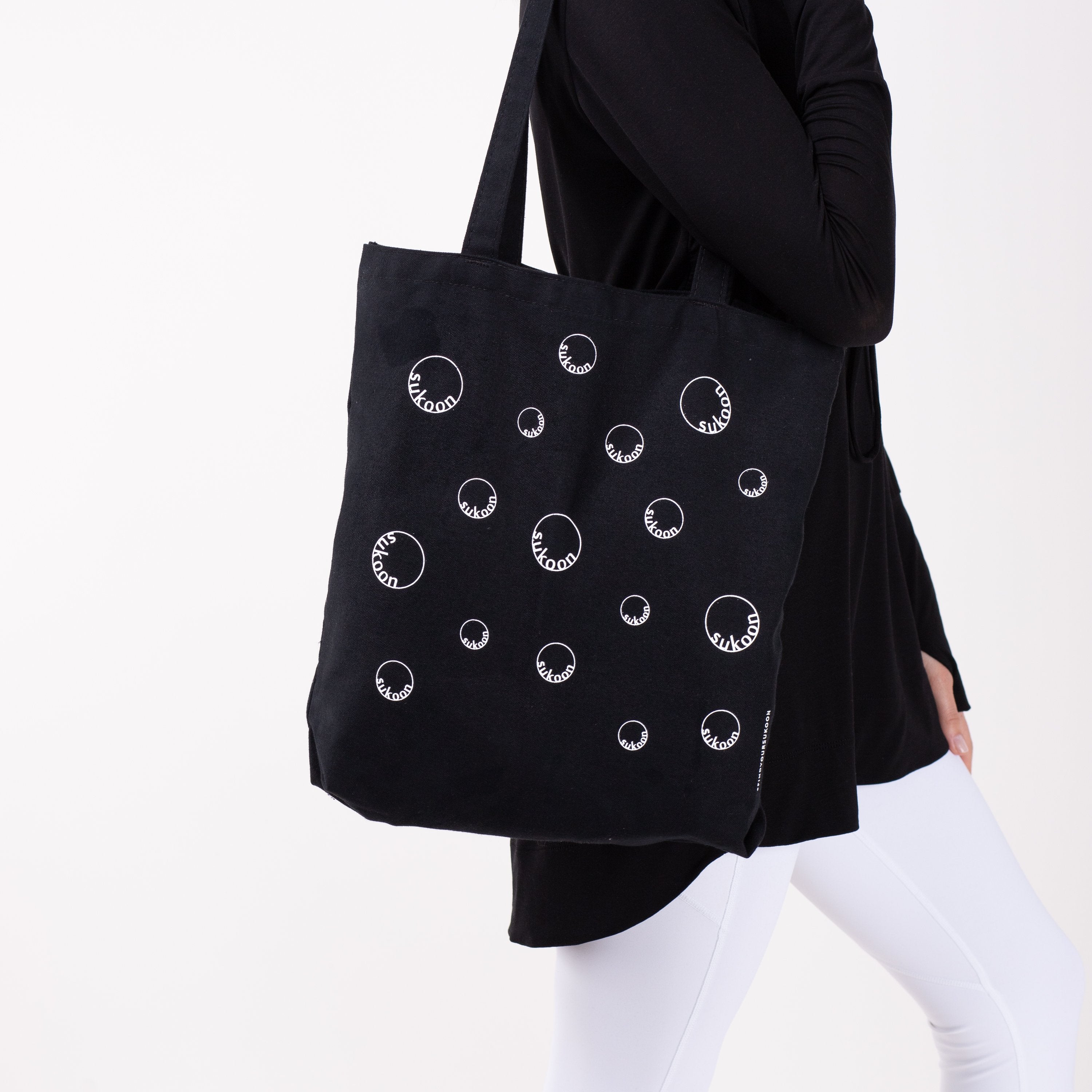 Black tote bag with all-over moon print on woman's arm.